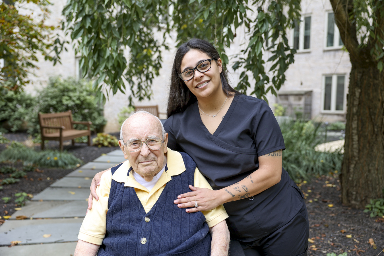 1W8A4033 Man with aide outside surrounded by trees