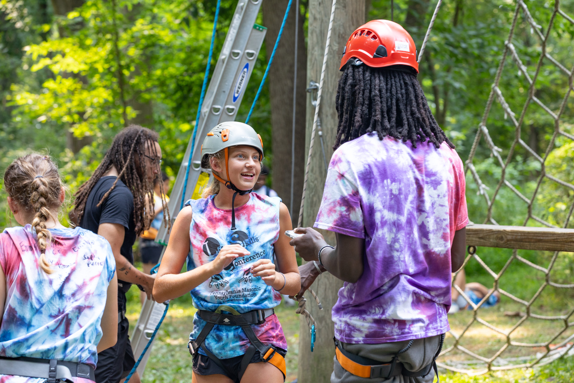 Teens dressed in climbing gear, happily talking outdoors.